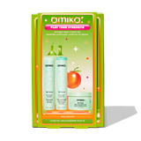 A product image of Amika's 'Play Your Strength' strength repair routine set in green packaging. The box displays three full-size products: The Kure Bond Repair Shampoo, Conditioner, and Intense Bond Repair Mask. The design includes vibrant colors and an orange illustration, with 'Play Your Strength' text in a pink banner